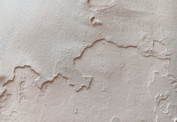 Close up of abstract texture peeling and flaking beige paint on a wall surface.