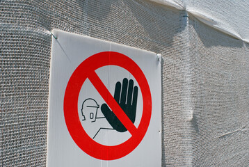 keep out warning sign on building draped in netting
