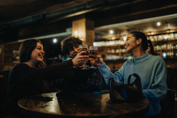 Three friends raise glasses in a warm, dimly lit bar, sharing smiles and conversation as they celebrate together after a night out.