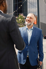 Business people standing and shake hands in front of modern office