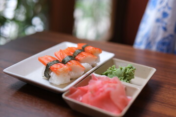 Salmon sushi nigiri with wasabi and pickled ginger, bright lighting, overhead composition on slate.