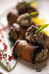 Baked eggplant rolls on a white plate .