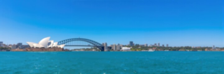 Fototapeta premium Blurred panoramic view of Opera House and Harbour Bridge on a clear sky day, suitable for graphic design backgrounds