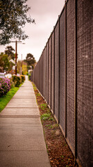 Obraz premium Dark textured panels form a soundproof barrier protecting a peaceful neighborhood from the noise of nearby traffic, enhancing the residential area's tranquility and comfort