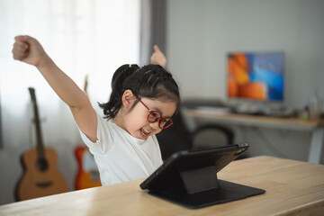 Excited Child Celebrating Success While Using Tablet at Home