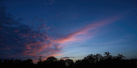 Evening sky with orange clouds and silhouetted trees and wires, serving as a background for text layout