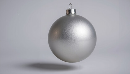 Silver Christmas ornament hanging against grey background  