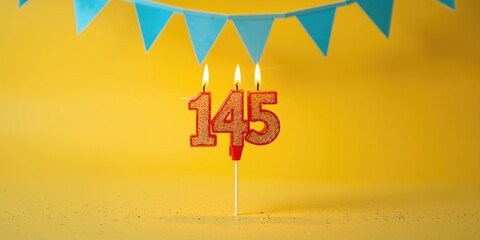 Lighted birthday candle displaying the number 145 against a yellow background with blue pennants, celebration and milestone recognition