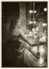 art photography sepia black and white color retro lady sits at makeup table looking into mirror with vintage lamps dressing room, sexy woman burlesque show cabaret dancer actress flapper girl 20s roar