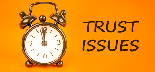 Trust issues symbol. Concept word Trust issues on beautiful orange paper. Beautiful black alarm clock. Beautiful orange paper background. Business trust issues concept. Copy space.