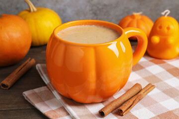 Warm pumpkin latte in cup on wooden table, closeup. Autumn atmosphere