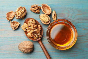 Honey in bowl and walnuts on light blue wooden table, flat lay
