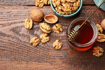 Honey in jar, dipper and walnuts on wooden table, flat lay. Space for text