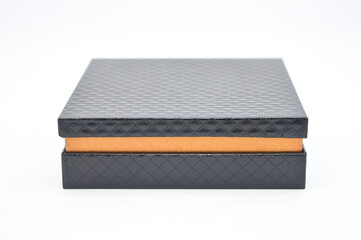 Elegant, square black gift box with a textured diamond pattern on the lid and base, separated by a contrasting peach-colored middle layer. Ideal for luxury packaging mockup and jewelry concept.