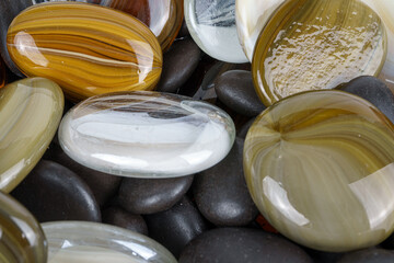 Polished decorative glass stones resting on smooth black pebbles.