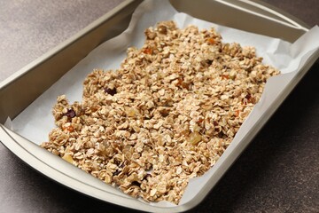 Making granola. Oat flakes with dried fruits in tray on grey table, closeup