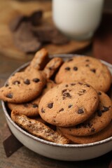 Yummy chocolate chip cookies in bowl on wooden table, closeup