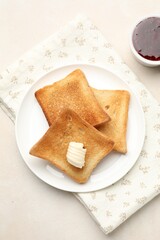 Slices of toasted bread, butter and jam on beige table, flat lay