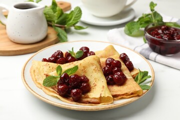 Delicious crepes served with cherry jam on white table, closeup