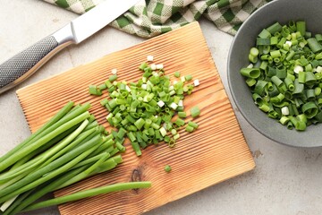 Cut green onions and knife on light grey table, flat lay