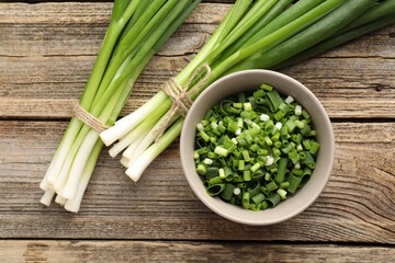 Fresh ripe green onions on wooden table, flat lay
