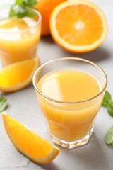 Fresh orange juice, mint and fruits on light table, closeup