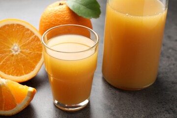 Fresh orange juice and fruits on grey table, closeup