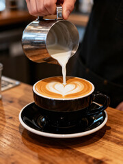 Barista Pouring Milk to Create Latte Art in a Cup of Coffee
