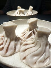 Georgian khinkali dumplings on round plates. Vertical food photo