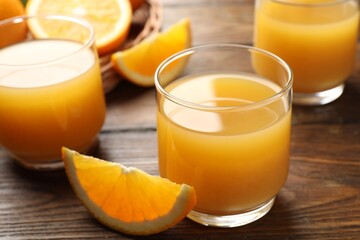 Fresh orange juice and fruits on wooden table, closeup