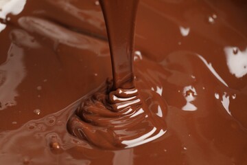 Tasty melted chocolate flowing down, closeup view