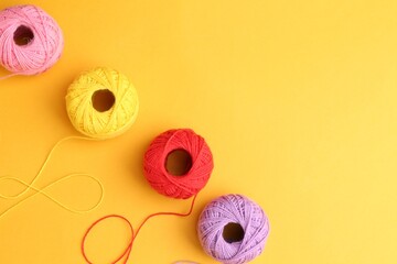 Balls of different yarns on yellow background, flat lay. Space for text