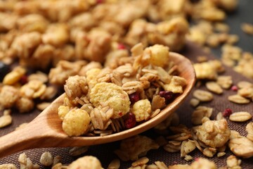 Tasty granola with dried fruits and spoon on table, closeup
