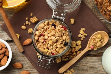 Tasty granola with dried fruits, nuts, milk and honey on wooden table, flat lay