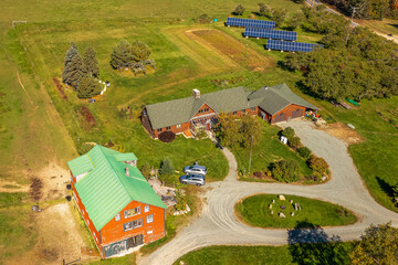 Aerial view rural countryside property with farm buildings, green fields, solar panels, gravel road.
