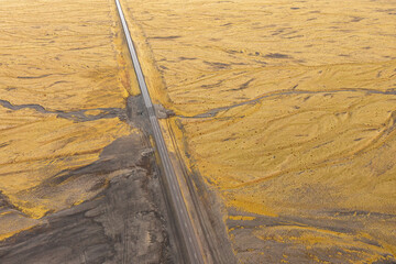 Long straight road through textured autumn plains of northeastern Iceland amidst volcanic landscapes