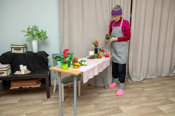 Older woman creates a beautiful flower arrangement. Craft master at work. Hobby and leisure activity for elderly people.