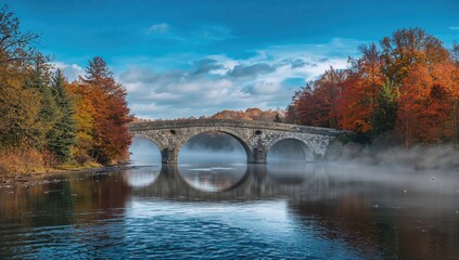 Obraz premium Ancient stone bridge crossing a river amidst colorful fall scenery in central Norway, ideal for editorial header backgrounds