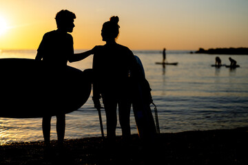 Two young people, friends with surfboard, going for surfing in the sea. Surfers carrying surfboards