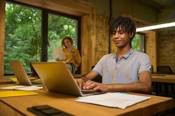 Adult man working on a laptop at a wooden desk