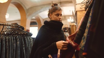 Young lady inspecting decorative clothing items attentively