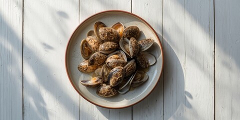 Fresh steamed cockles served on a ceramic plate against a rustic white wood background, suitable for seafood menu layout
