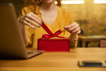 Close-up of hands opening a red gift box