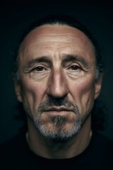 Middle aged man face portrait with serious expression, deep eyes, and dramatic lighting on dark background