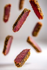 Spicy beef jerky pieces covered in pepper falling, showcasing a gourmet protein snack for healthy eating and energy