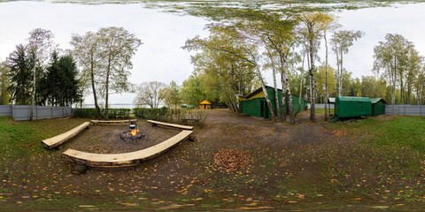 A full seamless spherical HDRI panorama with a 360-degree view of a forest recreation area. A green lawn for camping. A recreation center near water. VR content.