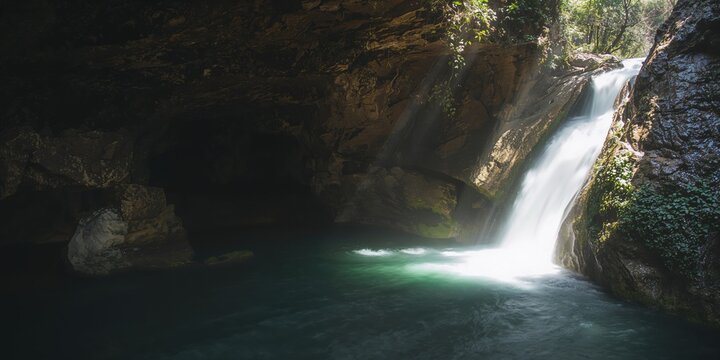 Blurred waterfall cascading over rocks inside a cave in sunny Andalusia, natural erosion processes - Powered by Adobe