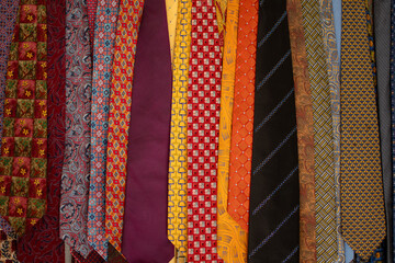 Colorful neckties hang from a bar in a closet.