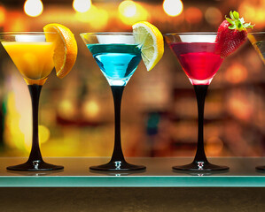 There are three cocktails on the bar, red, yellow, and blue