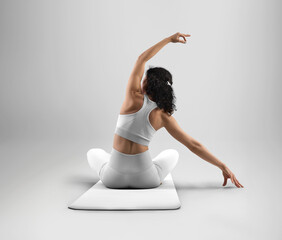 Mockup of white floor mat for yoga, trainer sits, dressed in a set of clothes for design, branding, back view.
